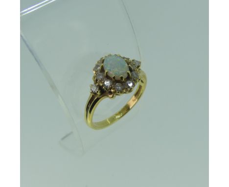 An opal and diamond cluster Ring,the oval central opal approx. 7.1mm long, with ten diamonds around and one on each shoulder,