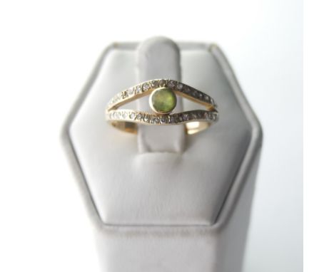 A peridot and diamond Ring,&nbsp;the split front with central collet set peridot with a row of diamond points above and below