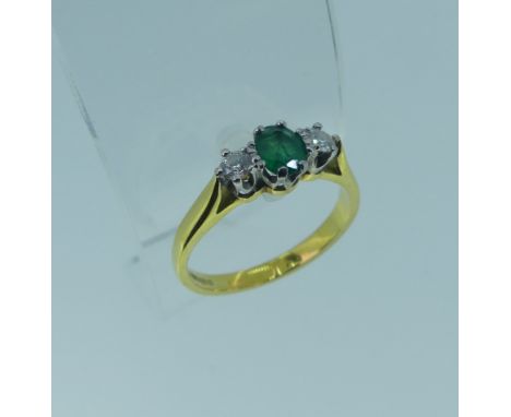 An emerald and diamond three stone Ring,&nbsp;the oval emerald approx. 5.1x3.9mm, with a circular diamond on either side, eac