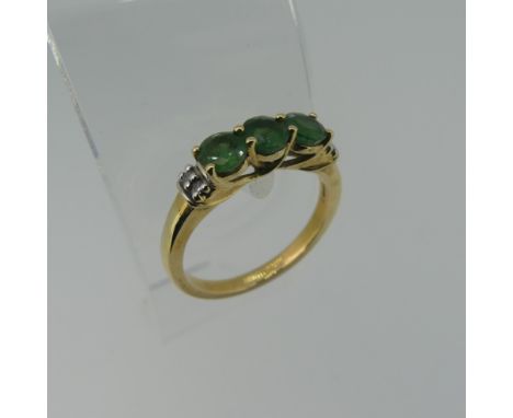 A three stone emerald Ring, the circular facetted stones approx 4.4mm diameter, with two diamond points on each shoulder, all