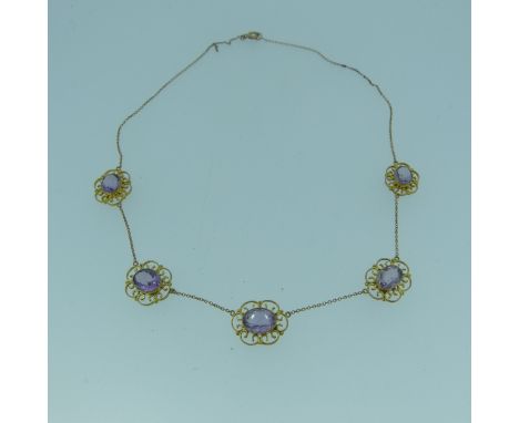 A Edwardian amethyst Necklace, the five oval facetted stones approx. 8.5mm long, millegrain set in scrolling mounts, trace ch