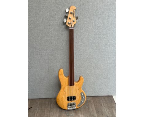An Ernie Ball Stingray bass guitar, natural body, hard case