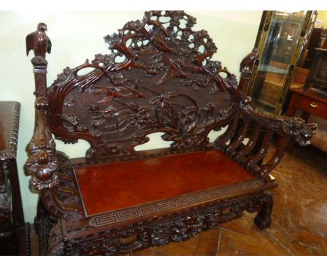 Heavily carved Chinese hardwood bench decorated with birds and foliage, dragon elbow rests and eagle finials 