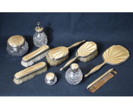 A George V golden guilloche enamel and silver mounted vanity set, comprising two hair brushes, two clothes brushes, a comb, a