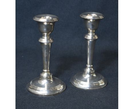 A pair of late Edwardian silver candlesticks, having circular sconces with step moulding, on knopped stems with further mould