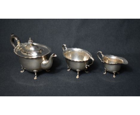 A late Edwardian silver three piece tea set, comprising a tea pot, sugar and cream each of oval form having Chippendale rim a