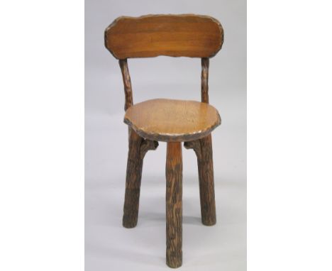 AN OVAL RUSTIC "CUTLERS" CHAIR with curving back, solid seat on three tree trunk legs.