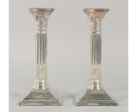 A PAIR OF SILVER PLATE CORINTHIAN COLUMN CANDLESTICKS 8ins high.