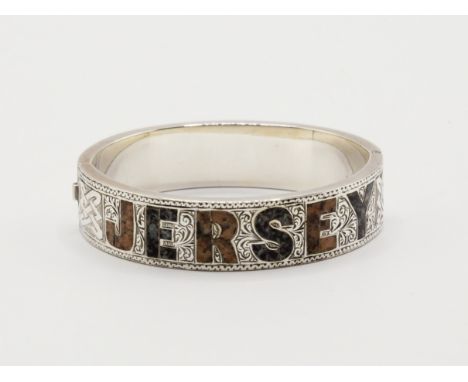 A rare silver granite inlaid Jersey souvenir bangle, early 20th century, with alternating inlaid red and blue granite spellin