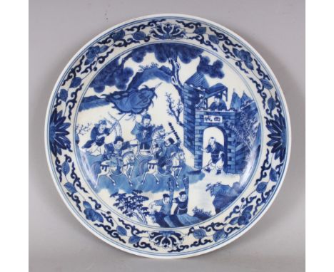 A CHINESE BLUE & WHITE PORCELAIN SAUCER DISH, decorated with warriors before a fortified settlement, the base with a six-char