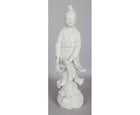 A FINE QUALITY CHINESE BLANC-DE-CHINE PORCELAIN FIGURE OF GUANYIN, standing on a wave plinth and holding a basket of fish, th