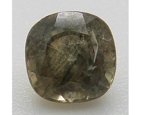 A loose cushion cut green sapphire showing rutile inclusions, approximately 0.7ct