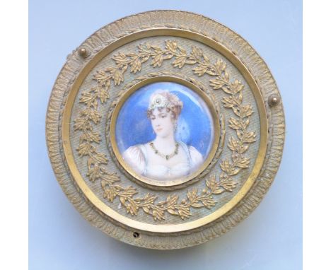 A 19th century gilt metal circular trinket box with portrait miniature of a lady with tiara and emerald necklace to centre, t