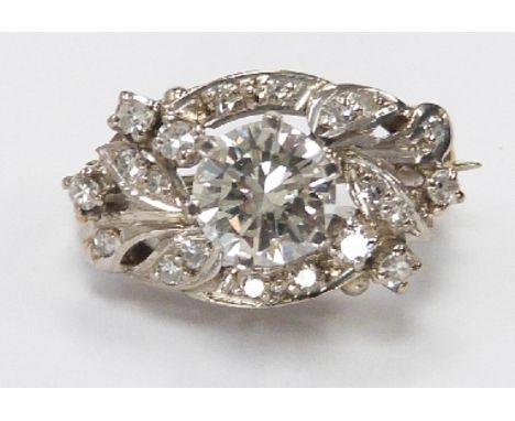 An 18ct white gold brooch set with a round brilliant cut diamond measuring approximately 1ct surrounded by further diamonds t