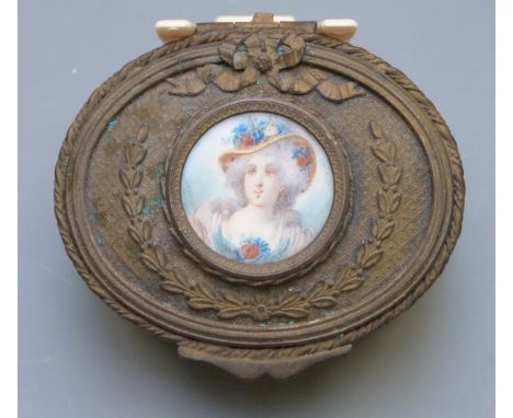 A 19th or early 20th century gilt metal oval trinket box with foliate and bow decoration, the top set with a portrait miniatu