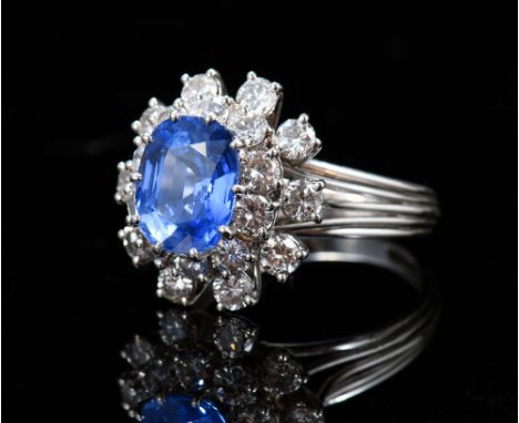 A platinum ring set with a cushion cut natural untreated cornflower blue sapphire of approximately 5.65ct surrounded by round