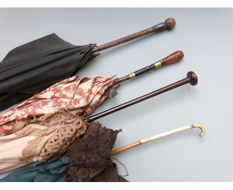 A collection of Edwardian lace parasols including lace, white metalmounted and gold stud inlaid amber