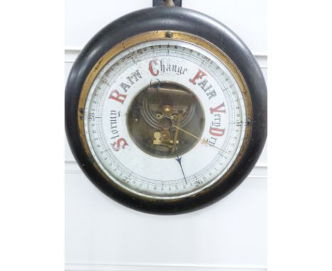 A late 19th/early 20thC circular aneroid barometer, the enamelled dial with red and black predictions, in ebonised case, 18cm