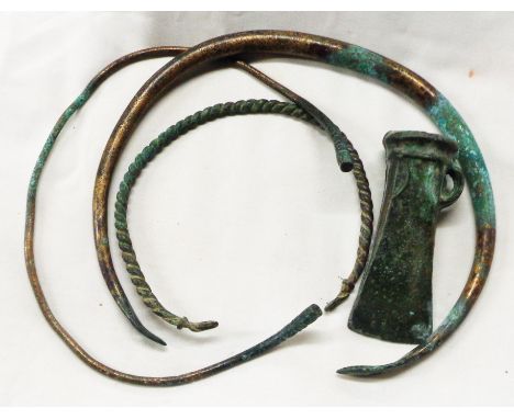 A bag containing three antique bronze torcs and a similar cast axe head