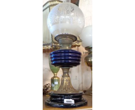 A brass oil lamp with Bristol blue glass reservoir and decorative frosted glass shade