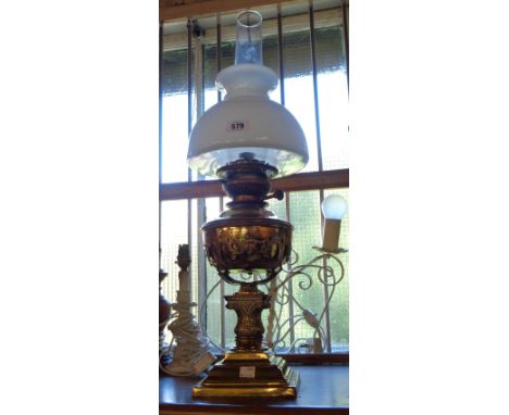 A Victorian brass oil lamp and stand, the stand of cast pedestal column form with scroll decoration, with glass chimney and o
