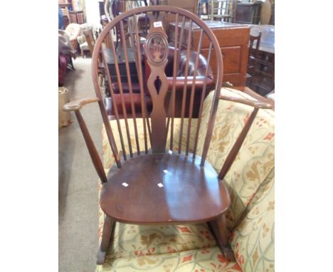 A vintage Ercol dark elm hoop stick back rocking chair with moulded seat, set on turned supports