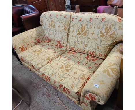 A 1.9m modern two seater settee with polychrome machine tapestry upholstery, set on turned legs with brass caps and casters