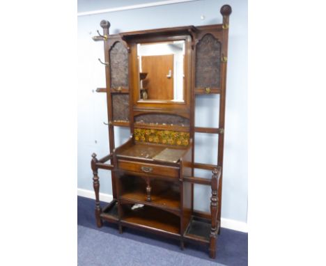 AN EDWARDIAN OAK HALLSTAND WITH BEVELLED RECTANGULAR MIRROR SURROUNDED BY PANELS OF BRONZED EMBOSSED WALLPAPER WITH FOUR FLOR