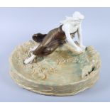 A Honenstein Art Nouveau table centre, formed as a girl sitting by a pond feeding a pond feeding a