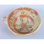 A 17th century slip decorated single-handled bowl, labelled "In the parish of St Botolphs, Aldgate