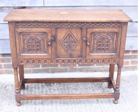 A carved oak side cabinet enclosed two doors, on turned and stretchered supports, 30" wide, a carved oak side table, fitted o