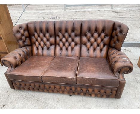 A BROWN LEATHER WING AND BUTTON BACK CHESTERFIELD THREE SEATER SOFA 