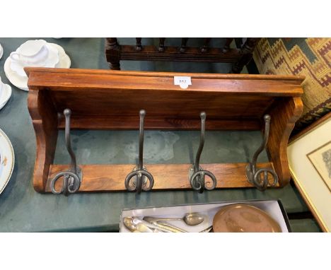 A WOODEN WALL SHELF WITH FOUR CAST HOOKS 