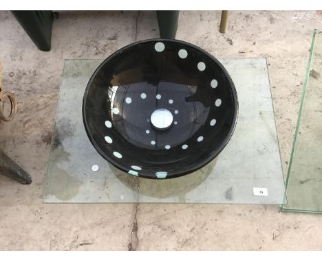 A BLACK GLASS ORNATE BASIN ON A GLASS TOP 