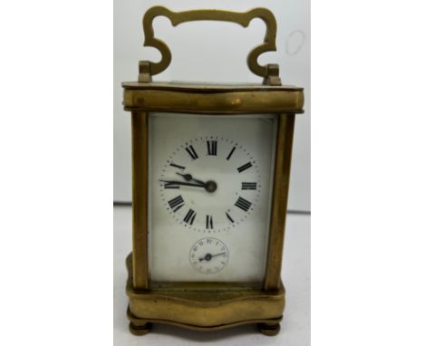 Brass carriage alarm clock with serpentine shaped case with French movement.Condition ReportWinds and goes.