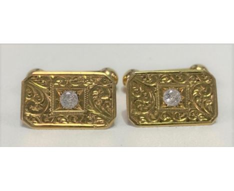 A pair of high purity gold cufflinks, the rectangular head foliate engraved, and each set with a white sapphire of 0.10ct spr