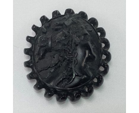 A 19th Century carved jet bracelet or choker roundel, carved in relief with a profile portrait of a woman with fruiting vine 