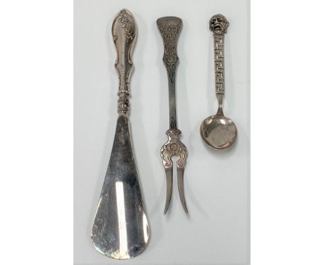 A George V silver handled shoe horn, Birmingham 1914; together with a white metal spoon with Greek key and mask handle, and a