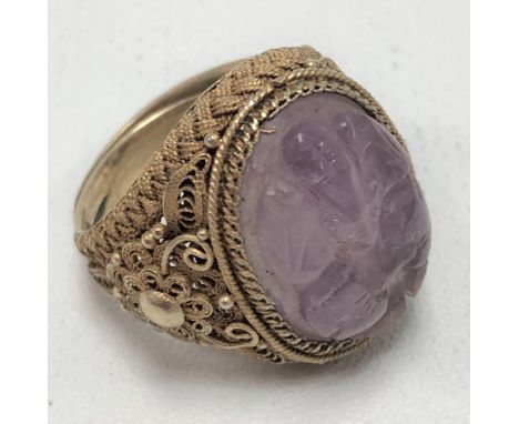 A Chinese silver gilt filigree ring, set an oval carved amethyst cabochon, decorated with a bat and two peaches, weight 8.6g 