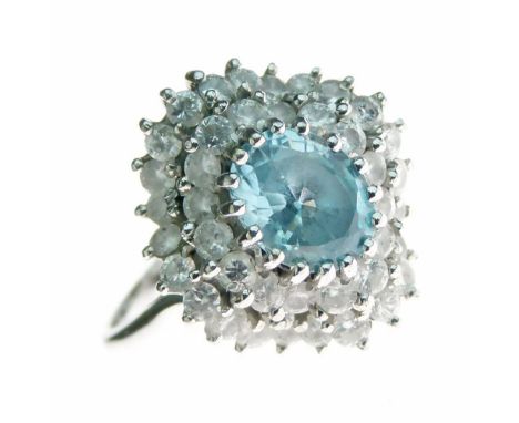 Aquamarine and diamond cluster ring, the white mount stamped '18ct', the oval cut aquamarine enclosed by two rows of brillian