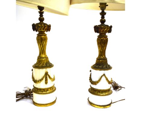 A PAIR OF FRENCH EMPIRE STYLE GILT METAL &amp; CERAMIC TABLE LAMPS  with ram's head, spiral flute, laurel swag and beaded dec