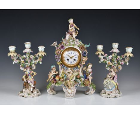 A Meissen style mantel clock garniture, the clock with applied putti and flowers, 19in. (48.2cm.) high, with a pair of matchi