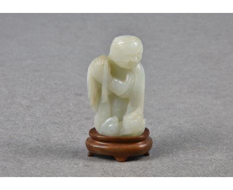 A Chinese pale celadon carving of an elderly man and fo dog, probably Qing dynasty, the robed man wearing a head band in his 