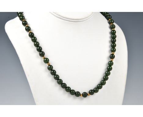 A dark spinach jade bead and 18ct gold necklace, the evenly sized 7mm. jade beads interspersed with small 18ct gold beads, wi
