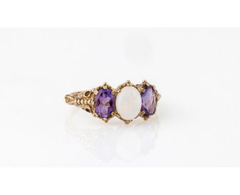 A 9ct yellow gold, opal and amethyst three stone ring, hallmarked London 2003, the central oval cabochon opal flanked by oval