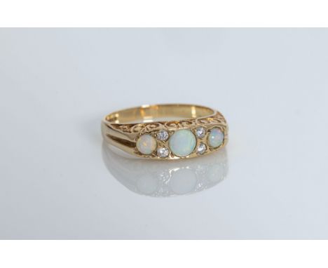 A 9ct yellow gold, opal and CZ seven stone ring, hallmarked Birm. 1994, with carved scroll sides, size N.. 