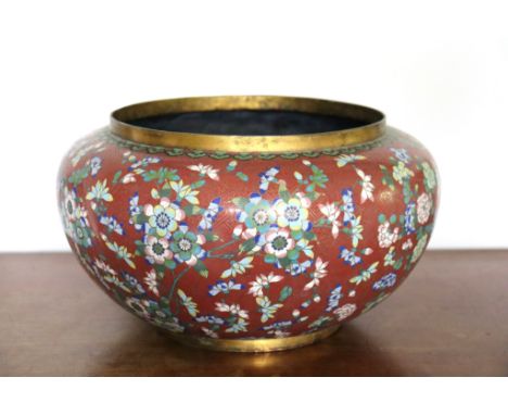 A Chinese cloisonné câche pot, decorated with blue, yellow and pink flowers on a red ground with key pattern cloisons, 13½in.