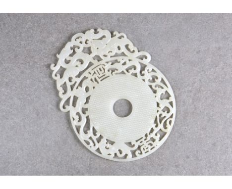 A large Chinese white jade dragon disc, probably 20th century, the rice grain centre within a border of chilong and other bea