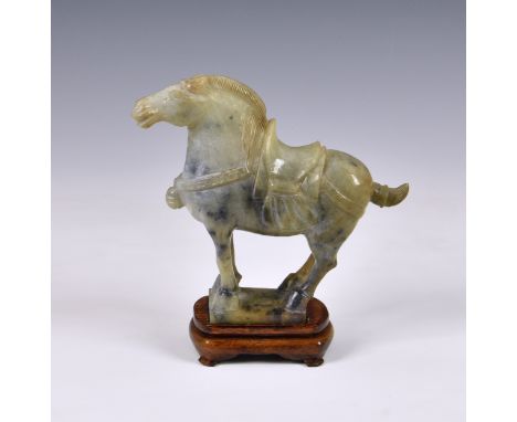 A Chinese carved green hardstone jade-style horse, modern, of typical Tang style, 7 ¾in. (19.7cm.) long, standing upon wooden