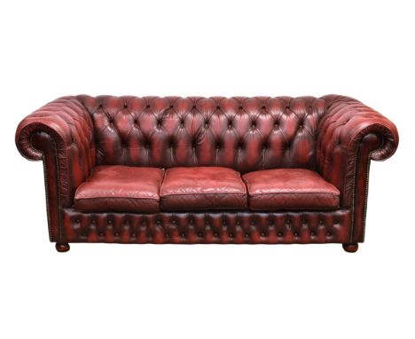 A red leather button back Chesterfield three seater sofa, with studded scroll arms, 77½ x 37in. (196 x 94cm.), 30½in. (77cm.)